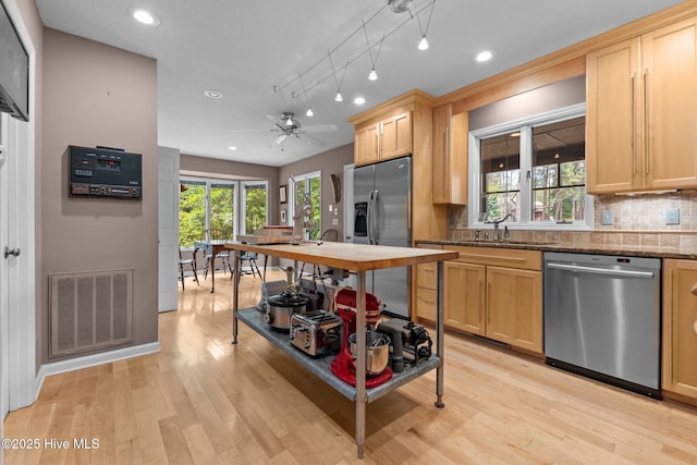 kitchen with appliances with stainless steel finishes, a sink, decorative backsplash, light brown cabinetry, and recessed lighting