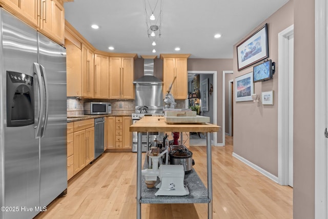 kitchen featuring appliances with stainless steel finishes, wall chimney range hood, light brown cabinetry, and recessed lighting