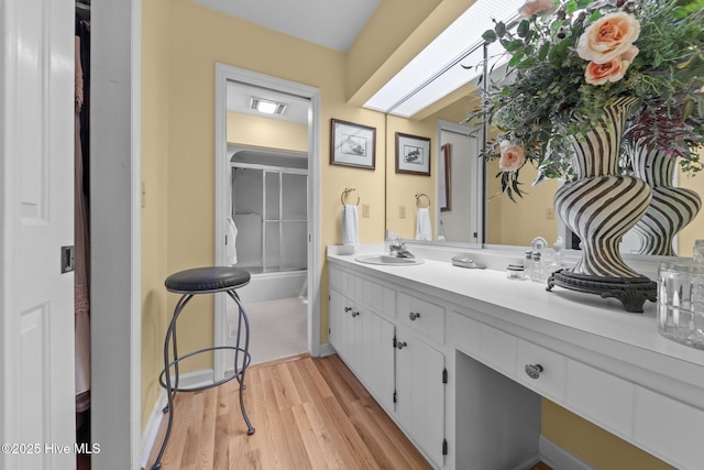 full bathroom with vanity, wood finished floors, and baseboards