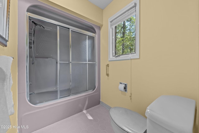 full bath with toilet, combined bath / shower with glass door, tile patterned flooring, and baseboards