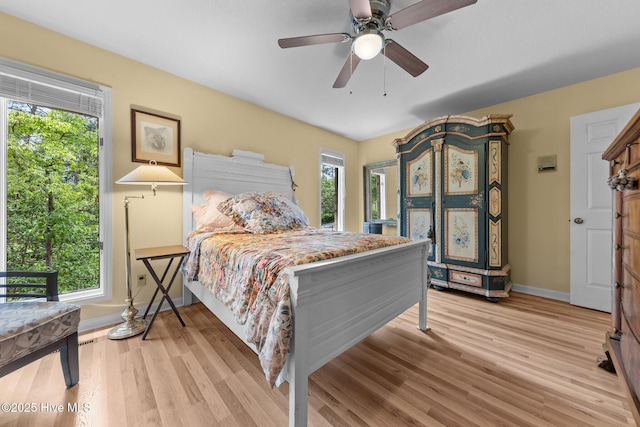 bedroom with baseboards, light wood finished floors, and a ceiling fan
