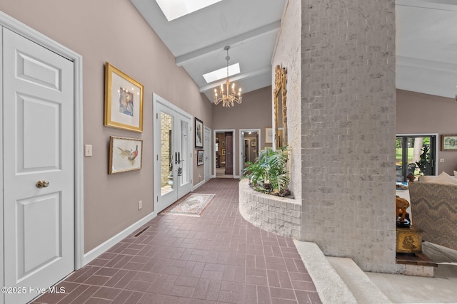 hall with a skylight, brick patterned flooring, a chandelier, baseboards, and high vaulted ceiling