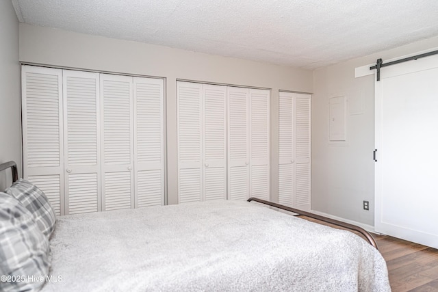 1100 Clarendon St Unit 606, Fayetteville, NC 28305 - bedroom featuring multiple closets, wood finished floors, a barn door, a textured ceiling, and baseboards