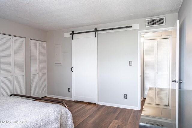 1100 Clarendon St Unit 606, Fayetteville, NC 28305 - bedroom with dark wood-style flooring, multiple closets, a textured ceiling, baseboards, and a barn door