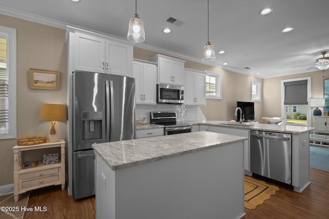 kitchen featuring visible vents, ornamental molding, a peninsula, a kitchen island, and stainless steel appliances
