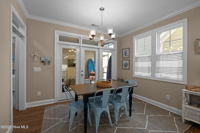 dining room with crown molding, visible vents, an inviting chandelier, wood finished floors, and baseboards