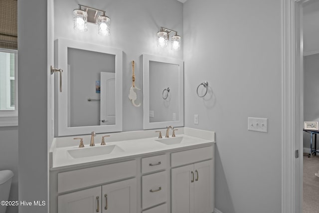 full bathroom featuring baseboards, double vanity, toilet, and a sink