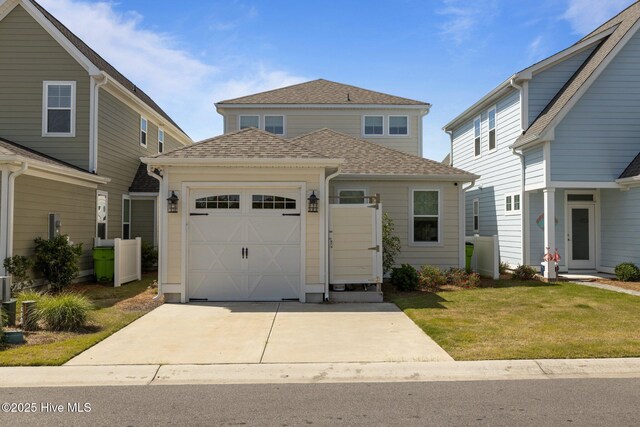 traditional home with an attached garage, a shingled roof, concrete driveway, and a front lawn