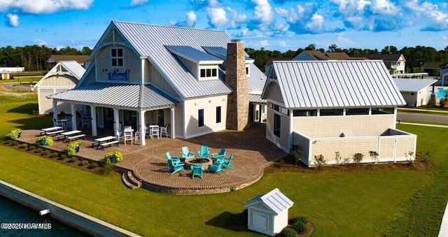 back of property with a patio area, a standing seam roof, a yard, a fire pit, and metal roof