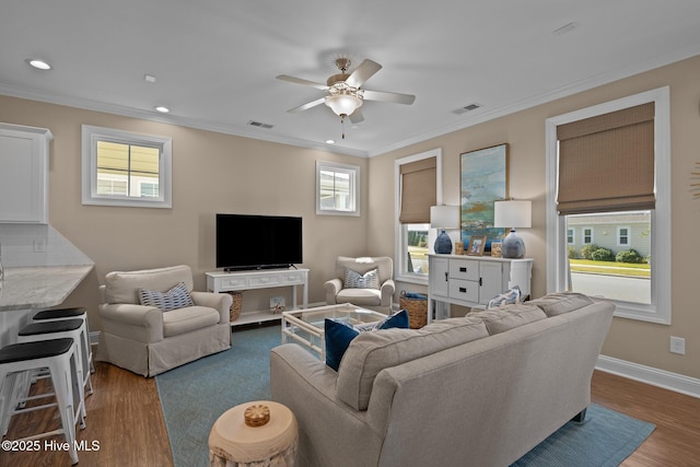 living room with crown molding, ceiling fan, wood finished floors, and visible vents