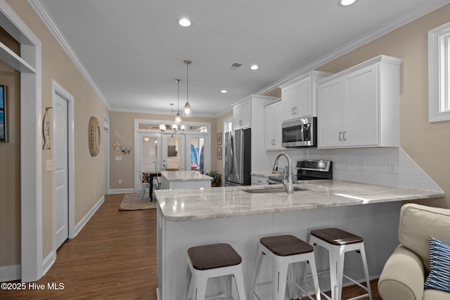 kitchen with appliances with stainless steel finishes, a center island, a peninsula, tasteful backsplash, and visible vents