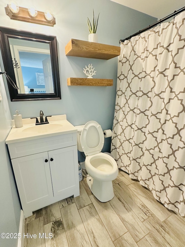 bathroom featuring toilet, wood finished floors, vanity, and a shower with shower curtain