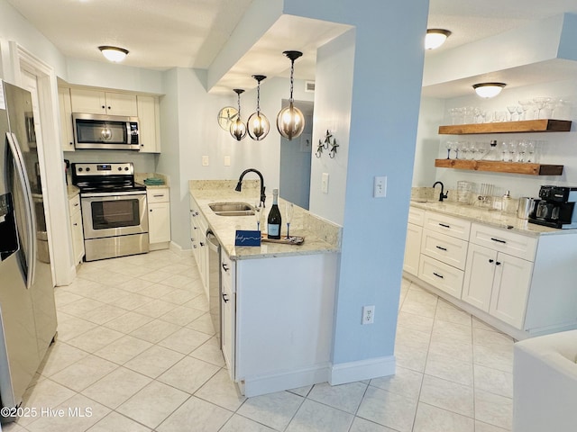 kitchen featuring light stone countertops, a sink, light tile patterned flooring, decorative light fixtures, and appliances with stainless steel finishes