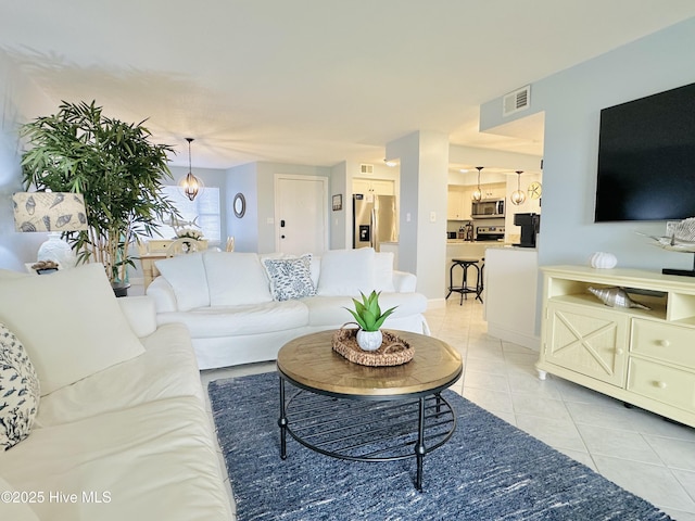living area featuring visible vents, light tile patterned floors, and an inviting chandelier