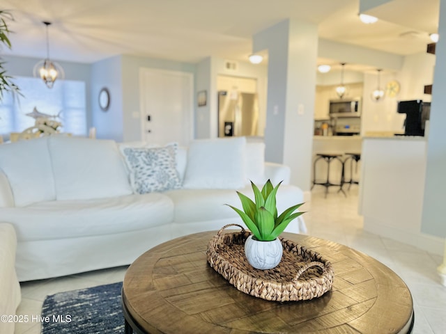 living area with light tile patterned flooring and a notable chandelier