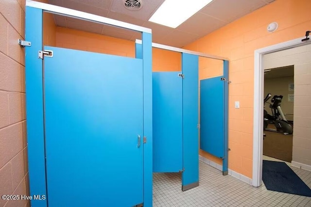 bathroom with concrete block wall, visible vents, and tile patterned floors