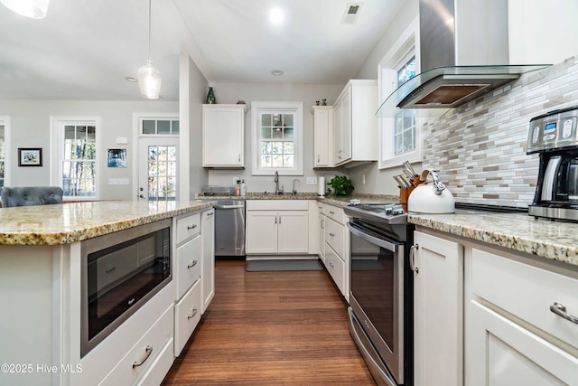 61 Spinnaker Point Rd N, Oriental, NC 28571 - kitchen with wall chimney exhaust hood, appliances with stainless steel finishes, dark wood finished floors, backsplash, and white cabinetry