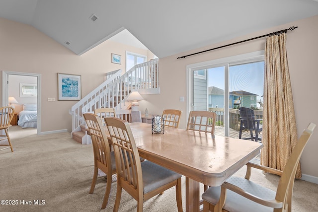 dining room with vaulted ceiling, stairway, light colored carpet, and baseboards