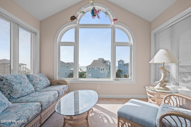 carpeted living room with healthy amount of natural light, lofted ceiling, and baseboards