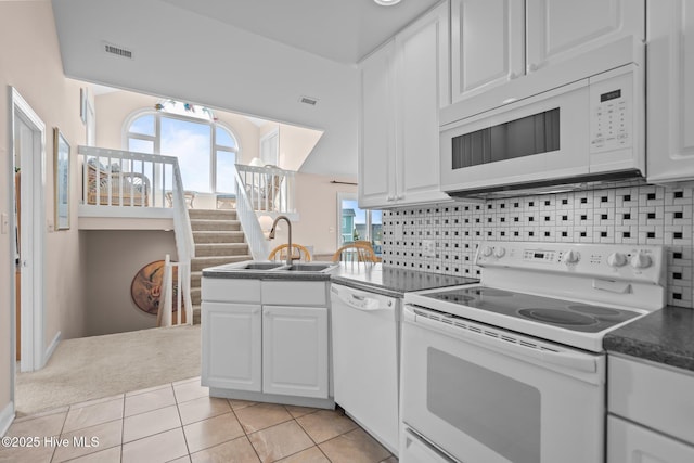 kitchen with white appliances, white cabinetry, a sink, and light tile patterned floors