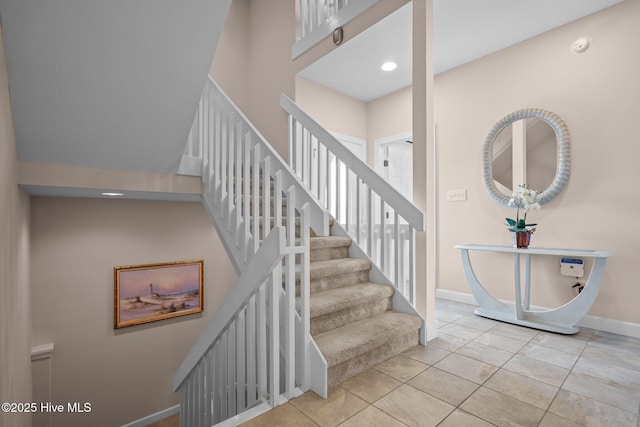 stairs featuring tile patterned flooring, baseboards, a towering ceiling, and recessed lighting