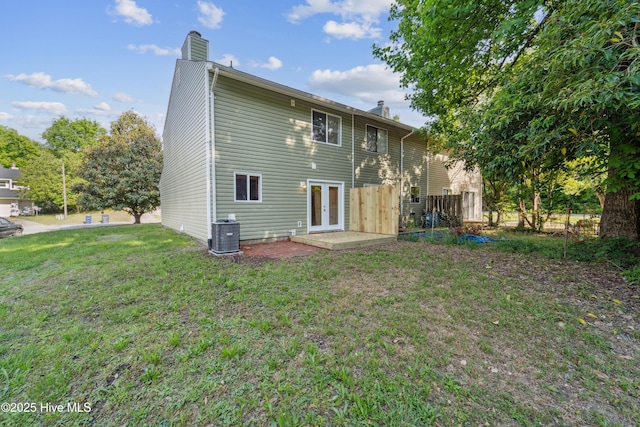 rear view of house with a chimney, central AC, french doors, and a lawn