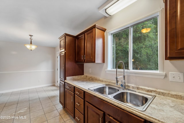 kitchen featuring decorative light fixtures, light countertops, light tile patterned floors, and a sink