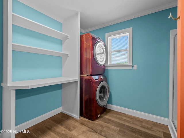 washroom with stacked washer and clothes dryer, laundry area, crown molding, baseboards, and wood finished floors