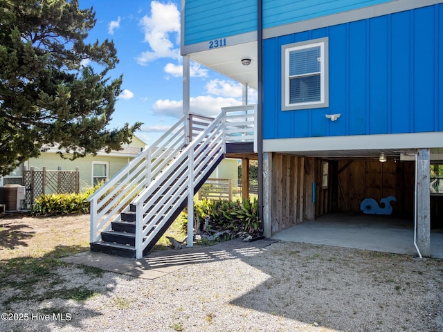 view of side of property featuring driveway, stairway, a carport, and board and batten siding