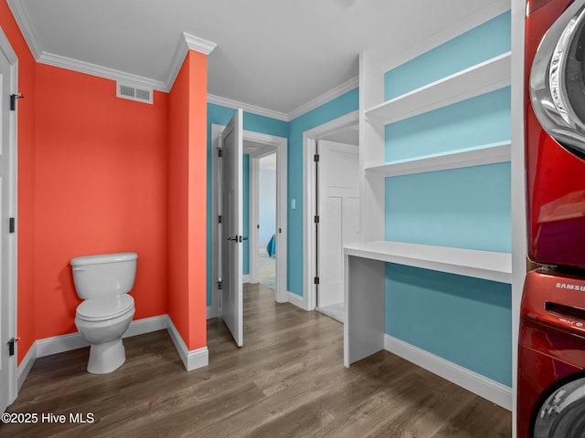 bathroom with stacked washer and dryer, wood finished floors, visible vents, and baseboards