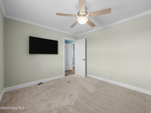 unfurnished bedroom featuring carpet, crown molding, a ceiling fan, and baseboards