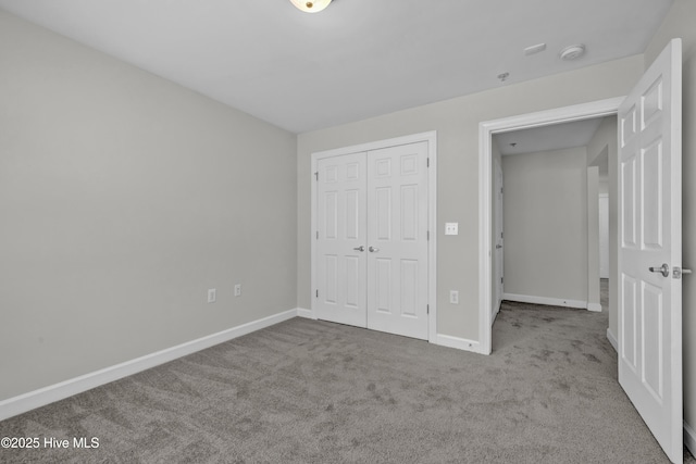 unfurnished bedroom featuring a closet, baseboards, and carpet flooring