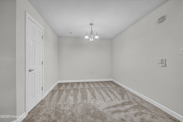 spare room with an inviting chandelier, baseboards, and carpet