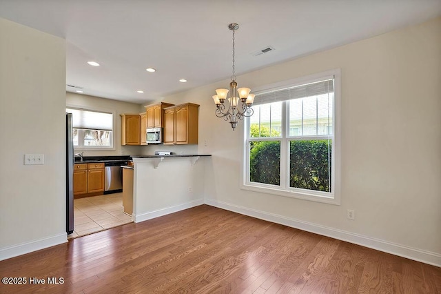 1008 Garden Club Way, Leland, NC 28451 - kitchen with appliances with stainless steel finishes, light wood-style floors, dark countertops, a chandelier, and a peninsula