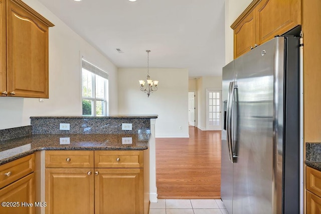 1008 Garden Club Way, Leland, NC 28451 - kitchen with stainless steel fridge with ice dispenser, a peninsula, a chandelier, and brown cabinetry