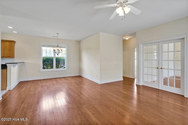 1008 Garden Club Way, Leland, NC 28451 - unfurnished living room featuring wood finished floors, a chandelier, baseboards, ceiling fan, and french doors