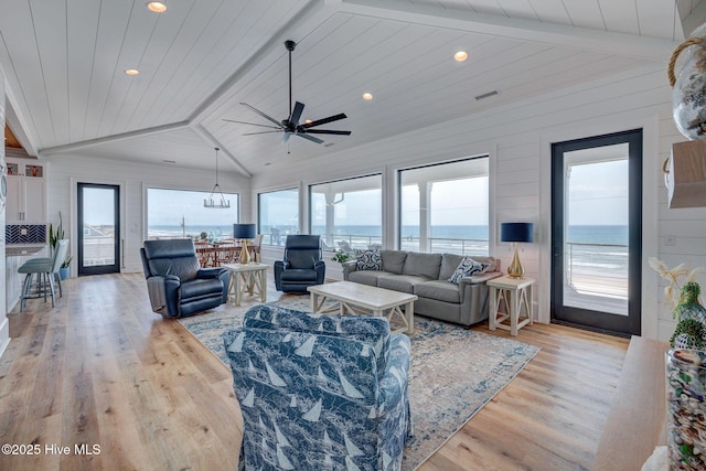 living room with vaulted ceiling with beams, a wealth of natural light, and light wood-style floors