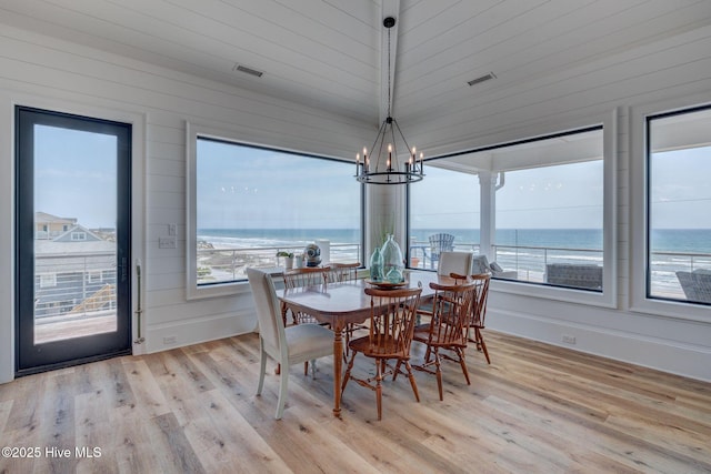 dining space with light wood finished floors, visible vents, and a chandelier