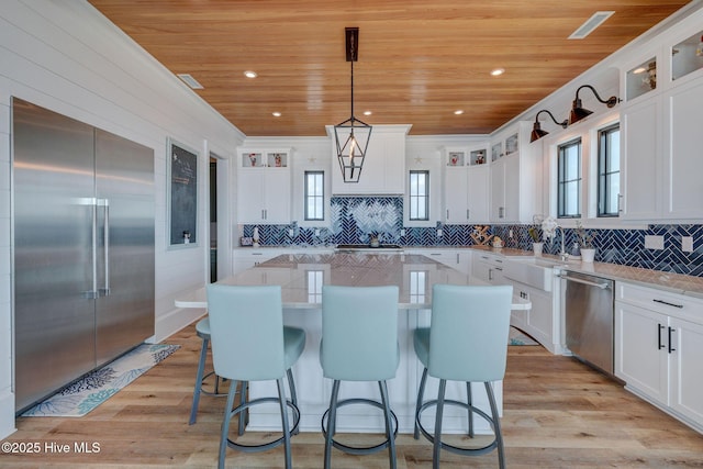 kitchen featuring glass insert cabinets, a sink, stainless steel appliances, a kitchen island, and wooden ceiling