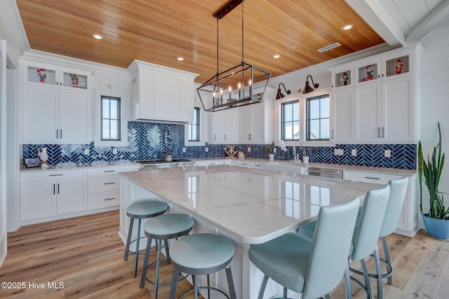 kitchen with a healthy amount of sunlight, a kitchen island, white cabinetry, and wooden ceiling