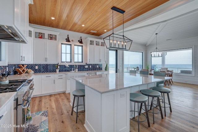 kitchen featuring wood ceiling, high end stove, a breakfast bar, a kitchen island, and custom exhaust hood