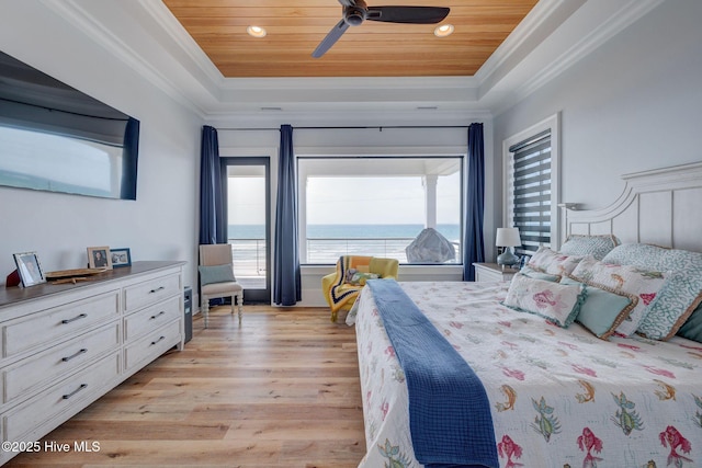 bedroom with crown molding, light wood finished floors, a ceiling fan, and a raised ceiling