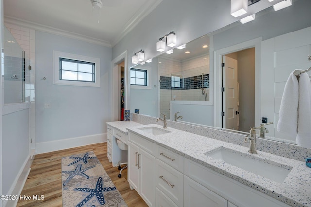 bathroom featuring ornamental molding, a stall shower, a sink, and wood finished floors