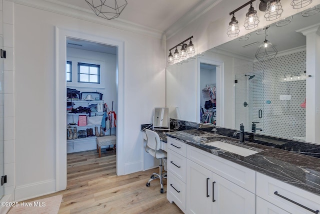 bathroom with wood finished floors, a spacious closet, ornamental molding, and a stall shower
