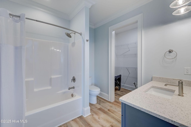 full bathroom with crown molding, toilet, wood finished floors, vanity, and a walk in closet