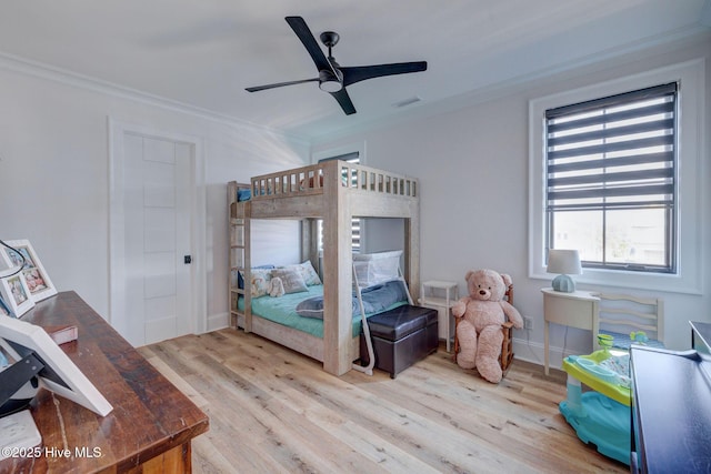 bedroom featuring wood finished floors, visible vents, crown molding, and a ceiling fan