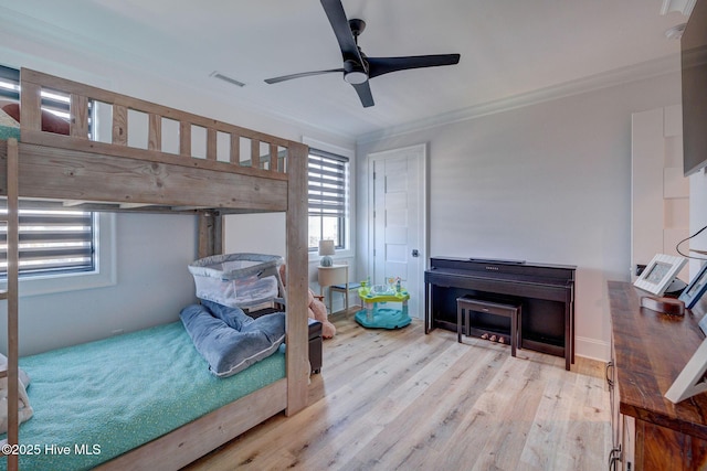 bedroom featuring wood finished floors, visible vents, ceiling fan, and crown molding