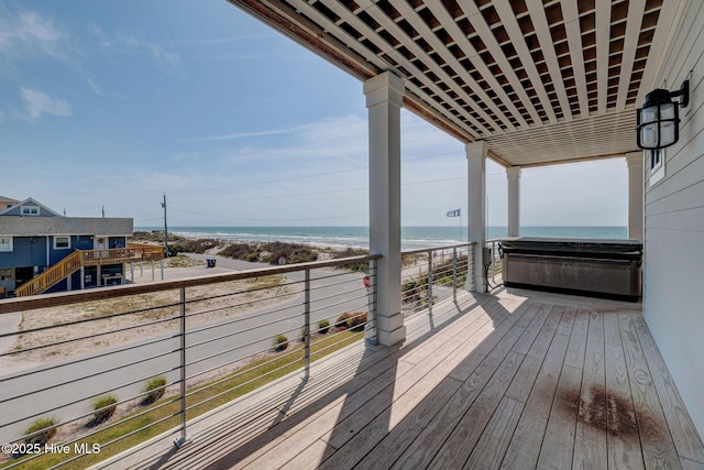 wooden terrace featuring a beach view and a water view
