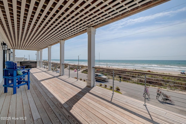 deck with a view of the beach, a water view, and a hot tub