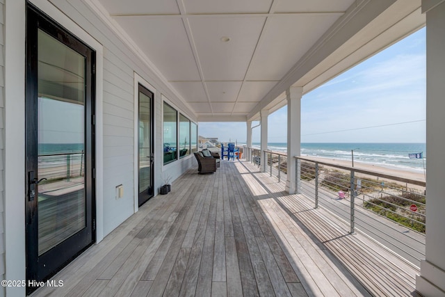 wooden deck with a water view and a view of the beach